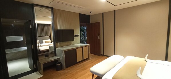 Une chambre d’hôtel moderne équipée d’un lit, d’une table de chevet, d’une télévision et d’un petit bureau.