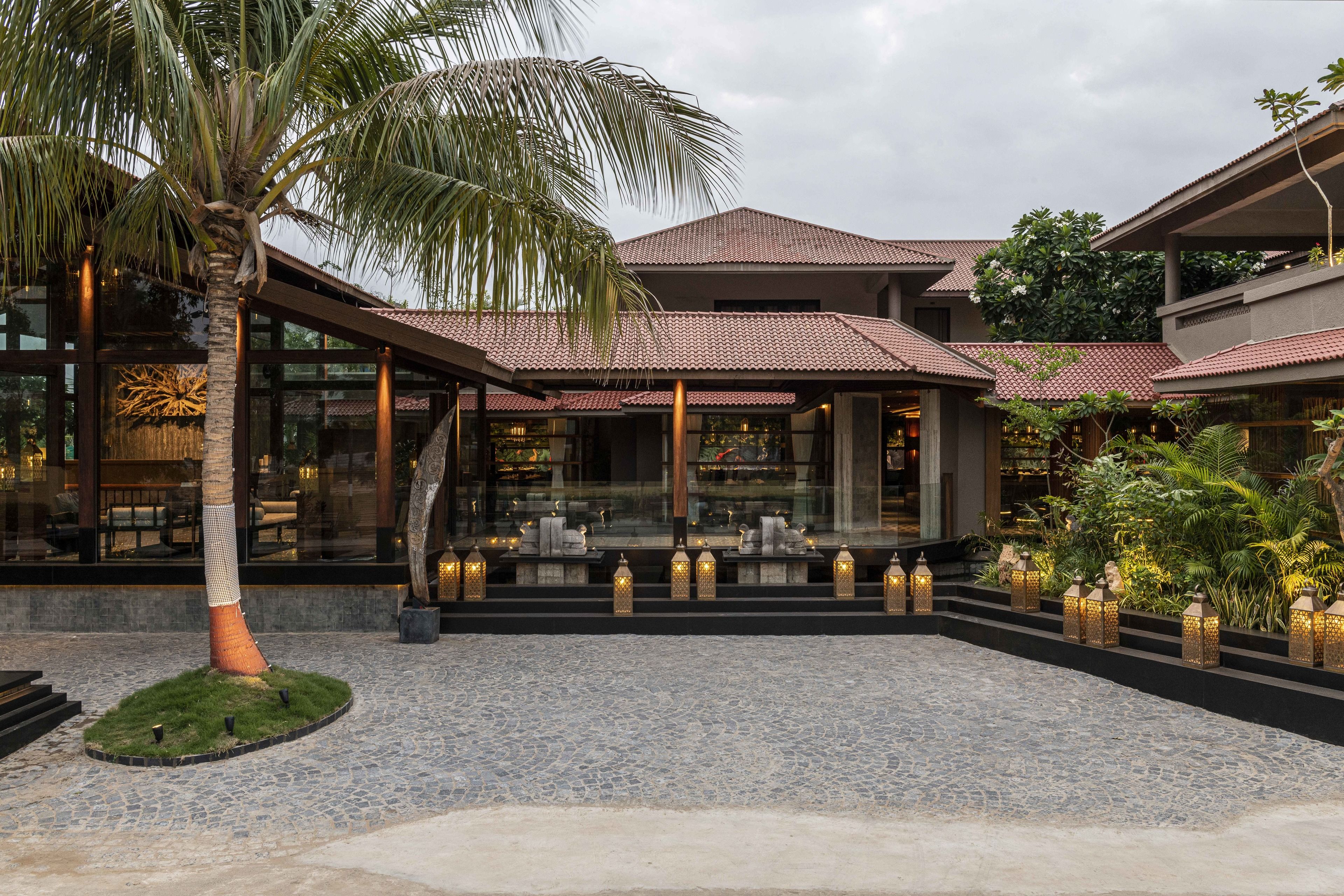 A modern building with a tiled roof, outdoor seating area, and decorative lanterns.