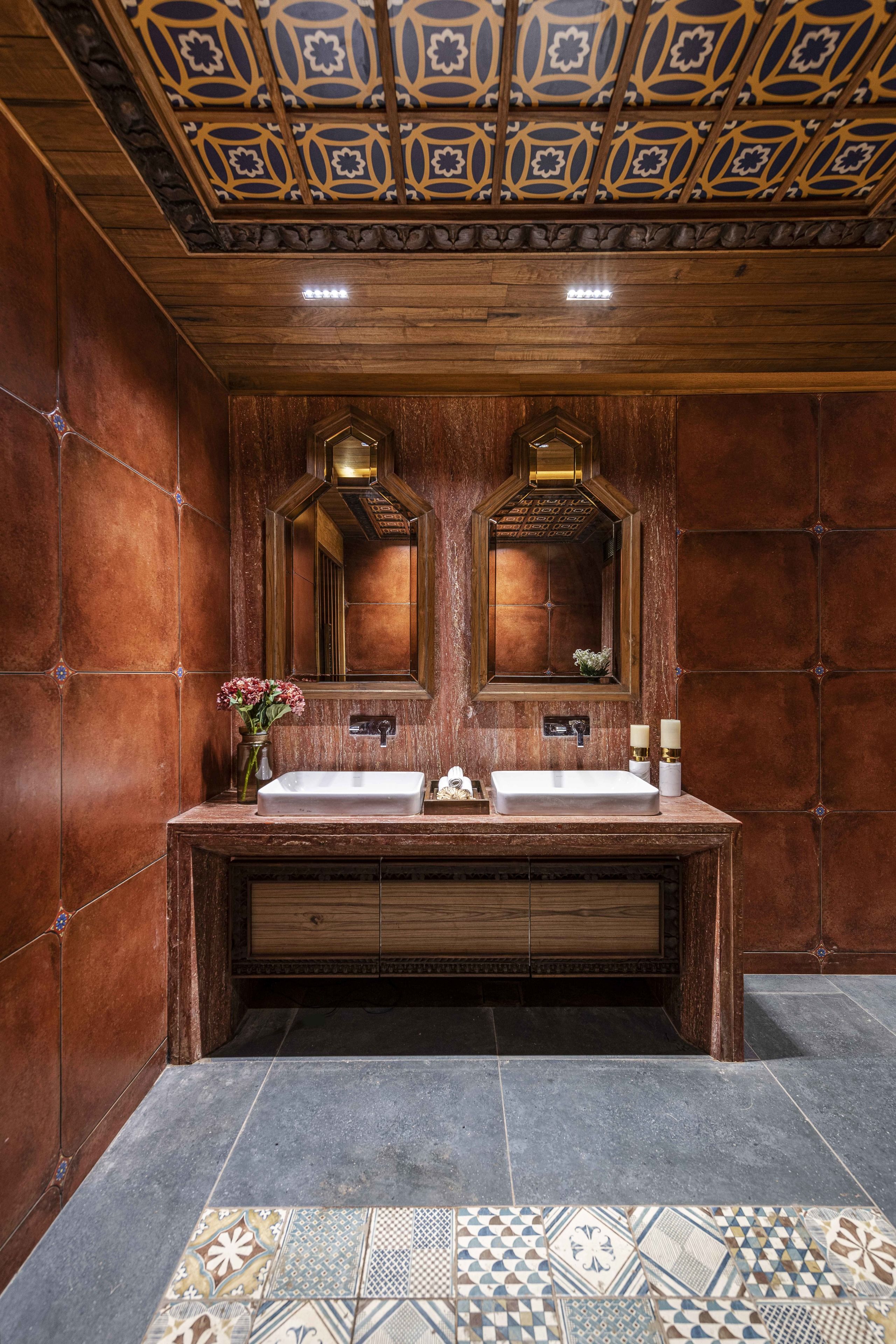 A bathroom with a wooden vanity, two sinks, a mirror, and a patterned floor.