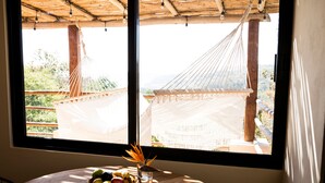 A room with a large window, a wooden table with a fruit bowl, and a hammock outside. - Casa Mono (Santa María Tonameca)