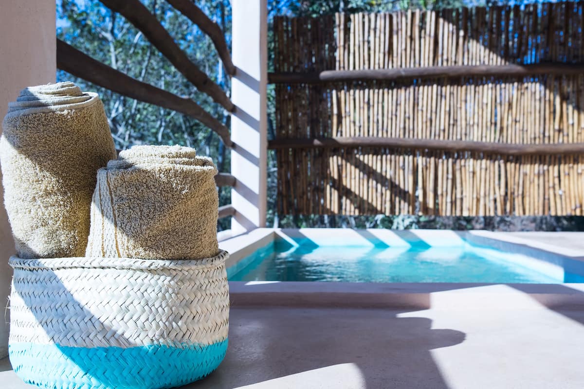 A pool area with a bamboo fence and a woven basket with towels.