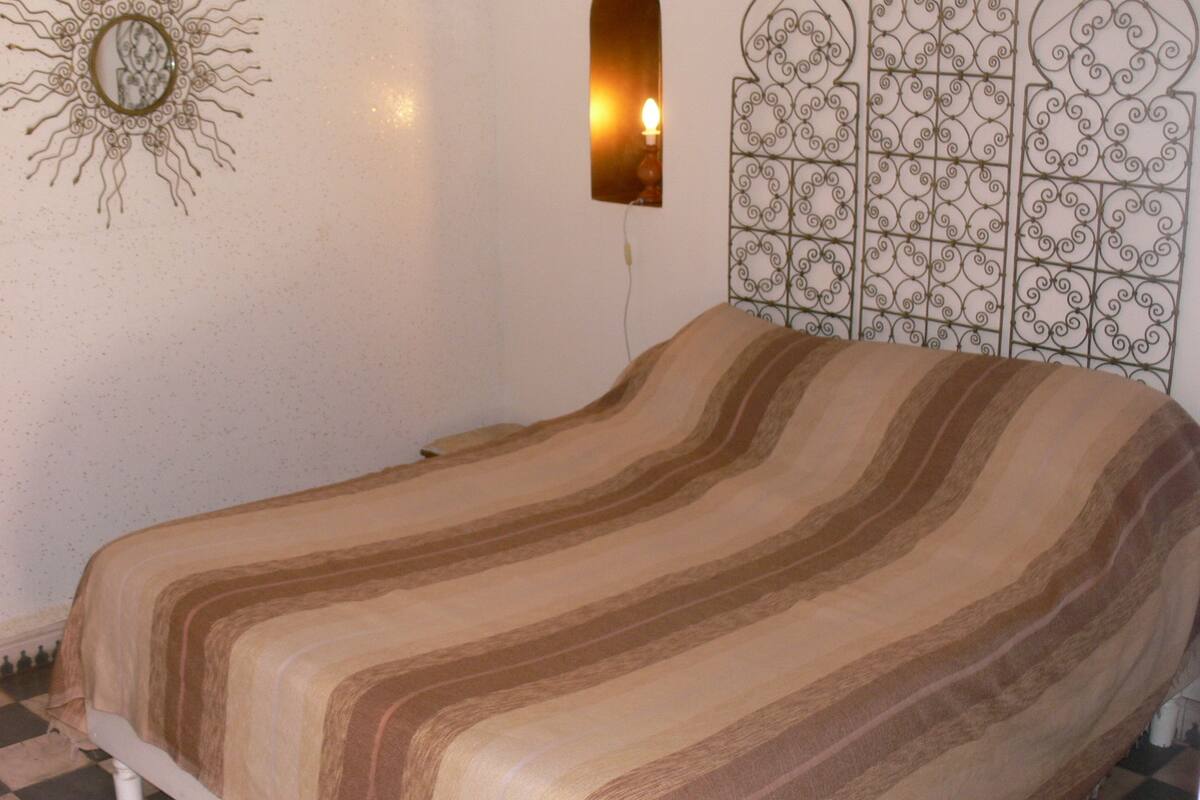 A room with a bed, a wall-mounted mirror, and a decorative metal panel.