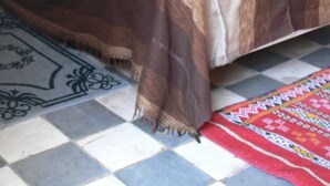 Una cama con un edredón estampado, un panel decorativo en la pared y un espejo.