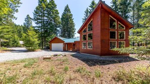 A cabin with a garage, a covered porch, and a large window. - Tall Pines (Cle Elum)