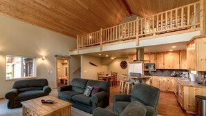A spacious living area with a loft bedroom, wooden furniture, and a kitchen with wooden cabinets. - Tall Pines (Cle Elum)