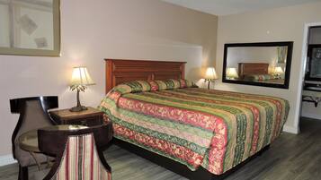 A hotel room with a large bed, two bedside lamps, a chair, a desk, and a mirror.