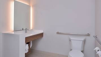 Un baño con lavabo blanco, espejo e inodoro.