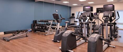 A gym with various exercise equipment, including treadmills, elliptical machines, and dumbbells.