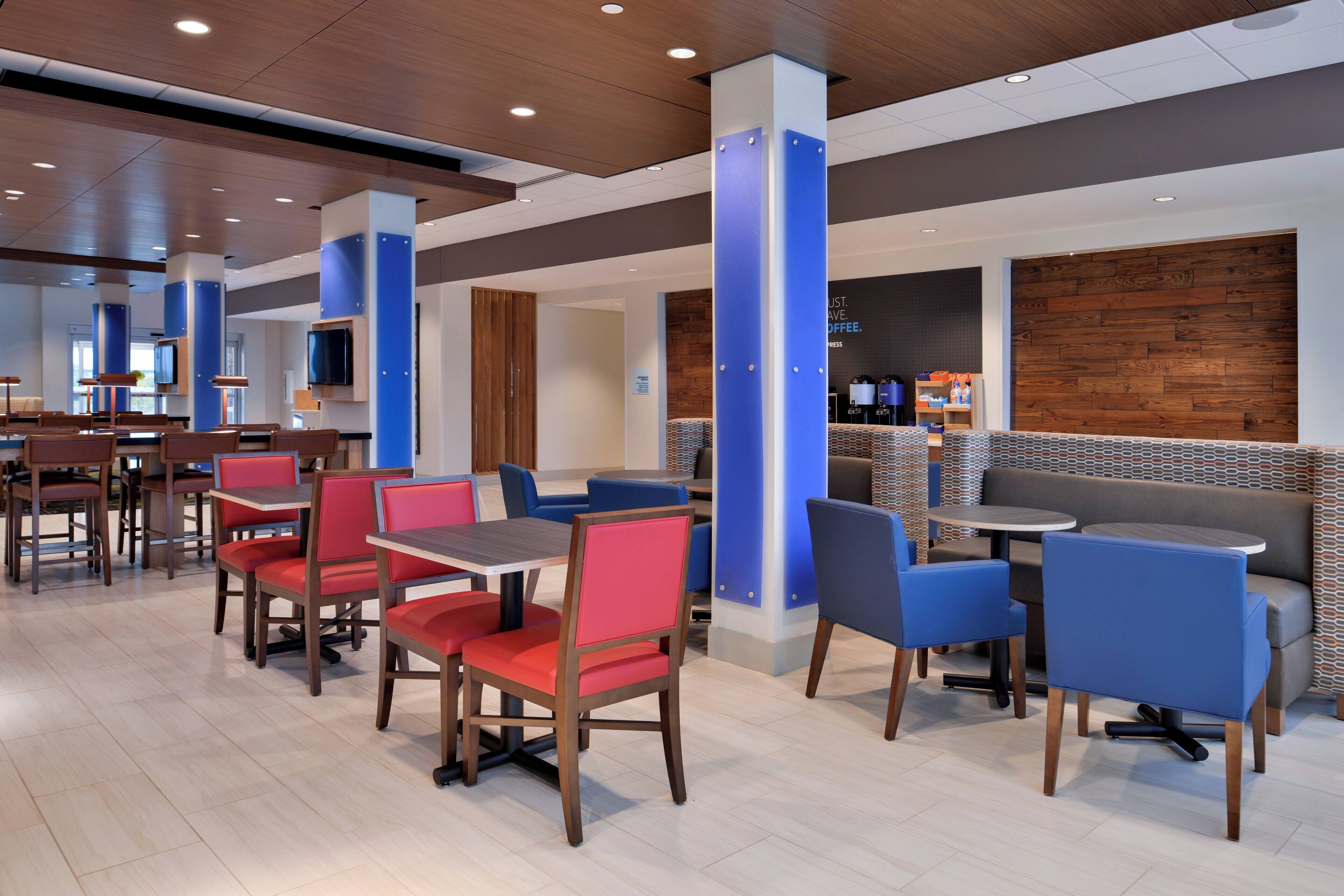 Un intérieur de restaurant moderne avec des banquettes et des tables, un plancher en bois et un espace dédié au bar à café.