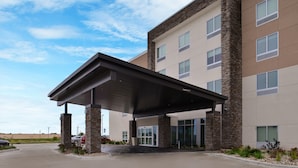 A modern hotel entrance with a covered walkway, stone pillars, and a parking lot. - Holiday Inn Express & Suites Marshalltown by IHG (Marshalltown)