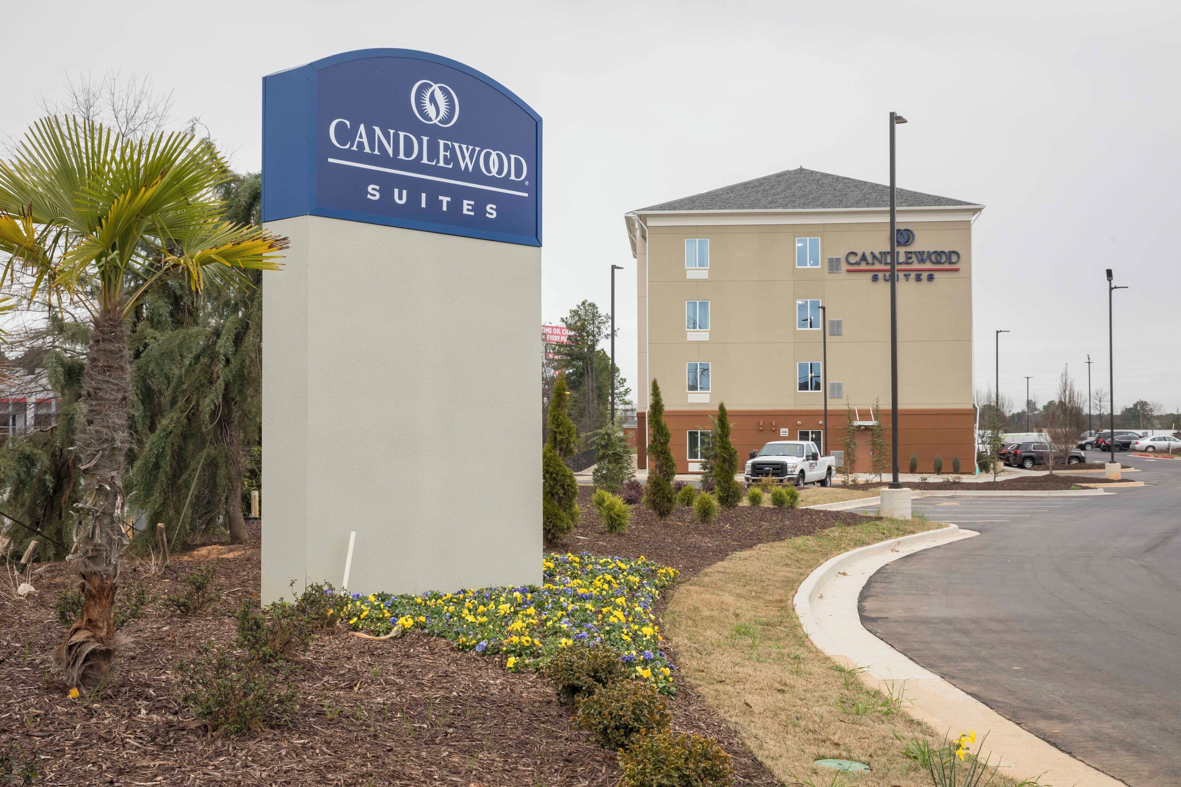 Señal de hotel para Candlewood Suites, con un edificio moderno al fondo.