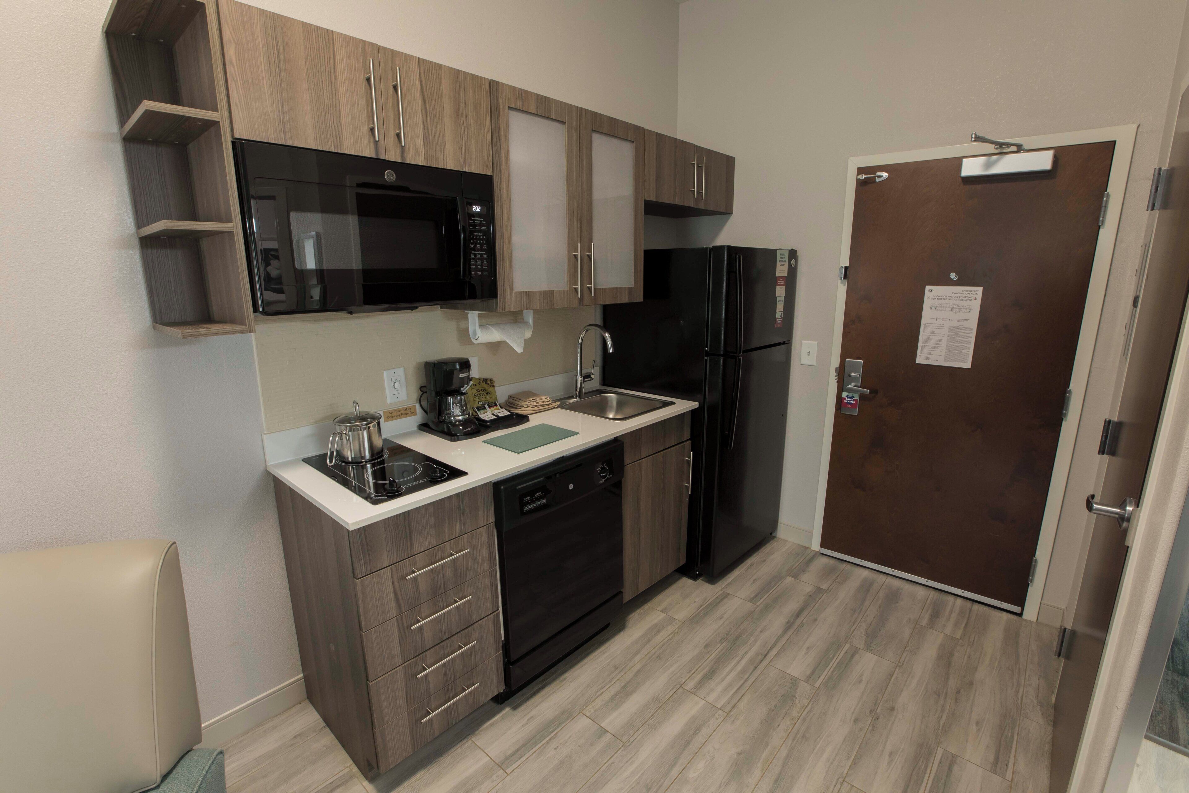 A compact kitchen with a microwave, stove, sink, and refrigerator.