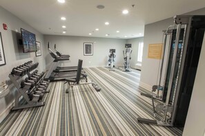 Academia com esteiras, halteres e máquinas de musculação.