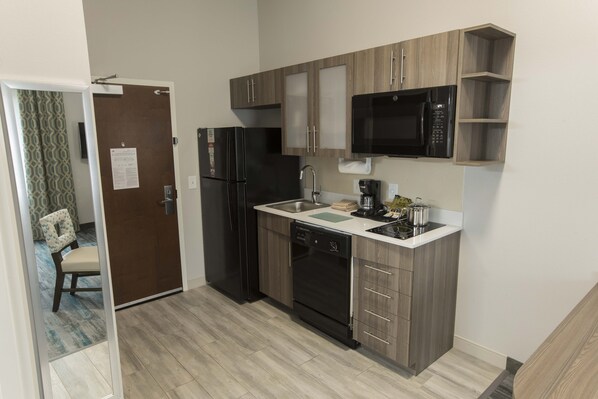 Eine moderne Küche mit Kühlschrank, Mikrowelle, Geschirrspüler und Holzschränken.