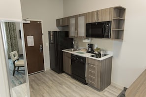 A modern kitchen with a refrigerator, microwave, dishwasher, and wooden cabinets.