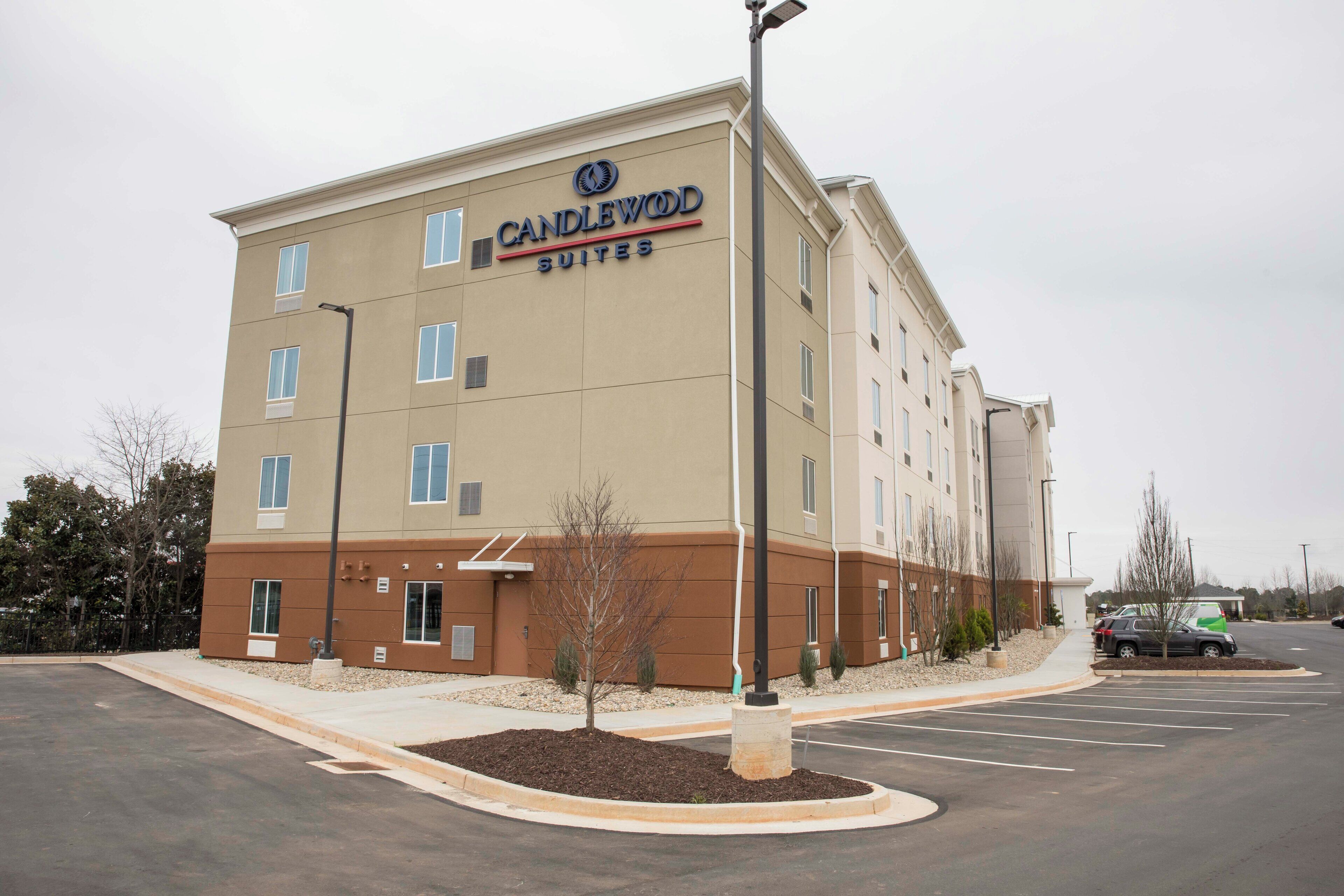 Un bâtiment de l’hôtel Candlewood Suites, avec un parking et quelques voitures.