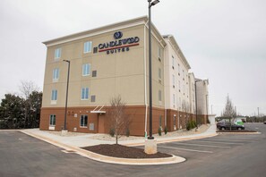 Edifício do hotel Candlewood Suites com estacionamento e alguns carros.