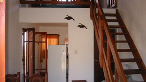 A dining area with wooden furniture, a staircase, and a wall-mounted bird decoration. - Cabañas Oma Lissi (Merlo)