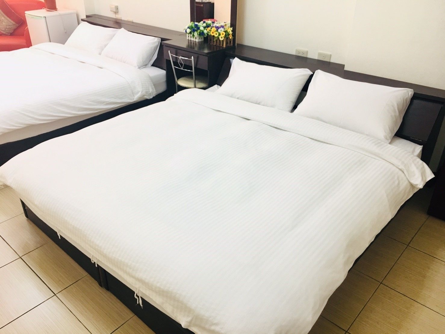 A hotel room with two beds, a desk, and a chair.