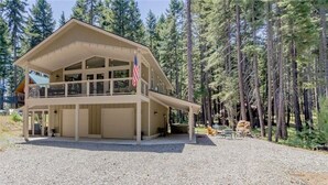 A two-story building with a balcony, surrounded by a forest. - Lake Cabins Lodge (Cle Elum)