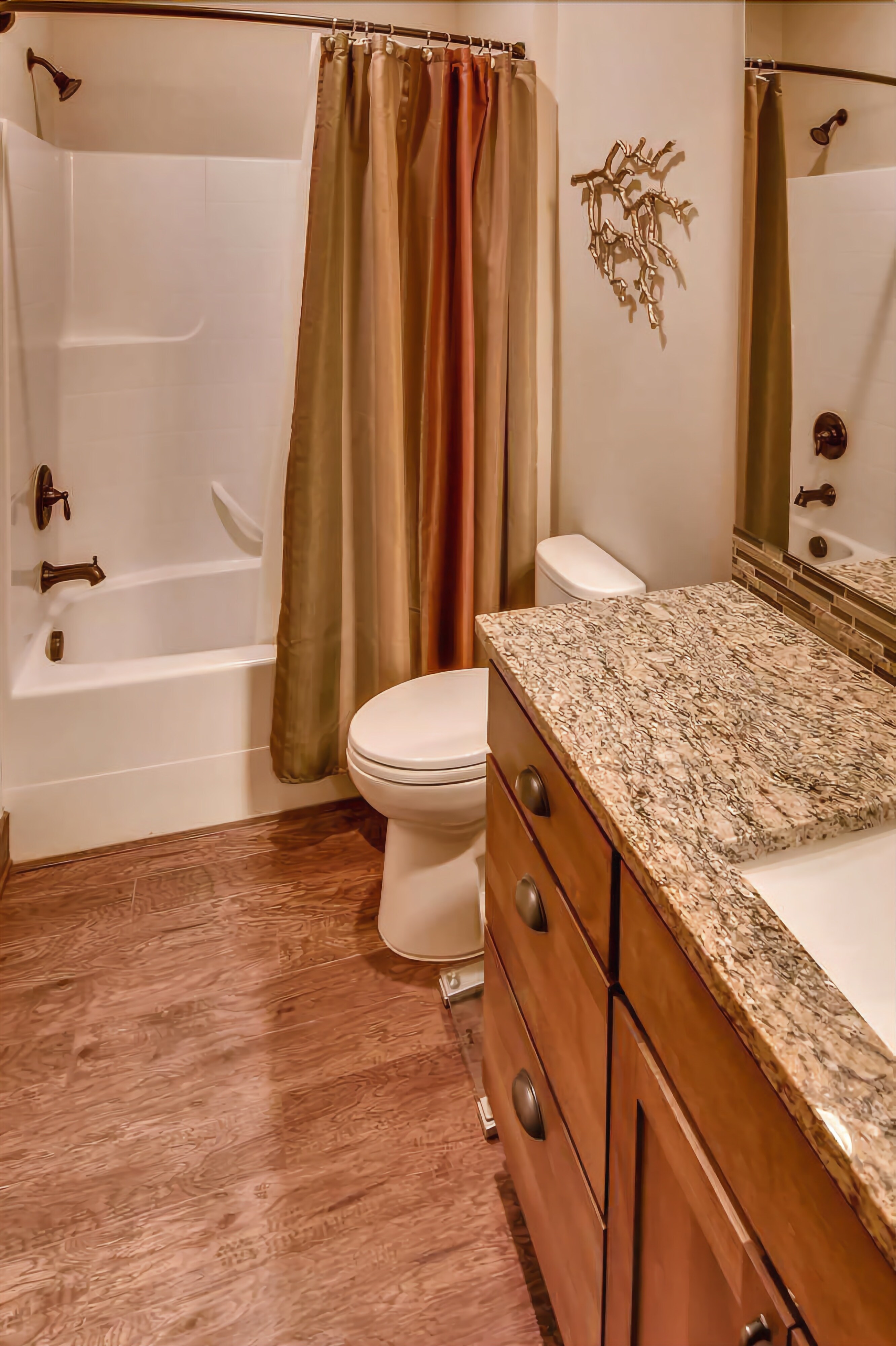 A bathroom with a bathtub, toilet, and vanity with a marble countertop.