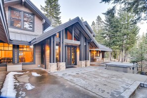 A modern house with a large front porch, stone pillars, and a covered patio area.