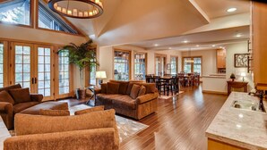 A spacious living area with a large sofa, a dining table, and a kitchen area with a marble countertop. - Pine Ridge Estate (Cle Elum)