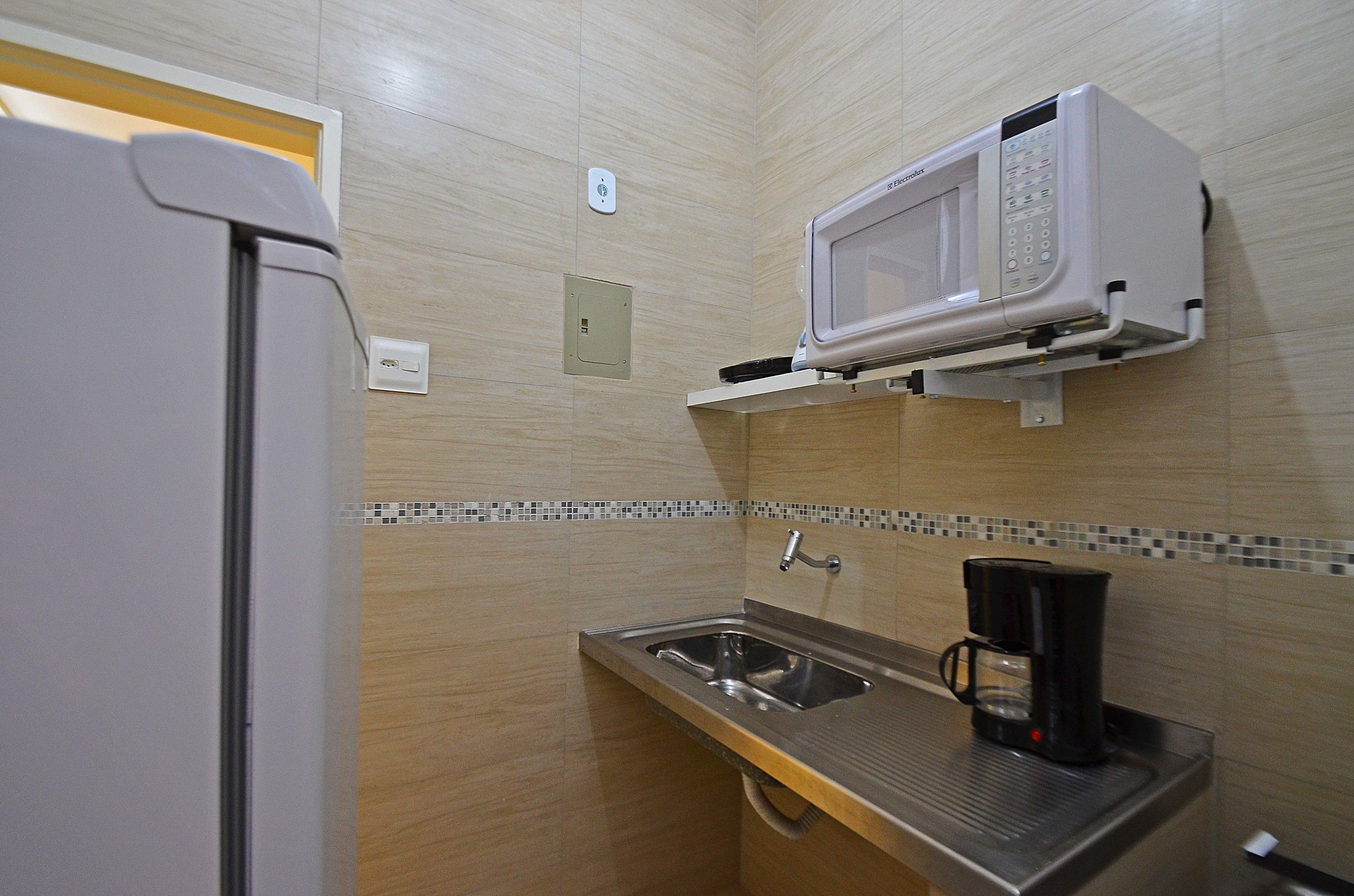 A compact kitchenette with a microwave, sink, and coffee maker.