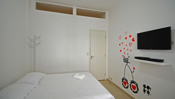 A bedroom with a bed, a TV mounted on the wall, and a door. - Rio Rentals 021- C074 Studio na quadra da praia de Copacabana (Rio de Janeiro)