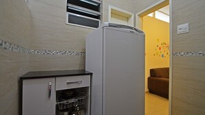 A compact kitchen with a refrigerator, a built-in oven, and a small cabinet with pots. - Rio Rentals 021- C074 Studio na quadra da praia de Copacabana (Rio de Janeiro)