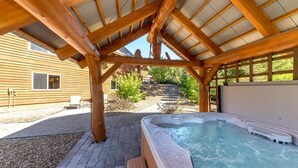 Una estructura de pérgola de madera con un jacuzzi debajo de un techo inclinado.