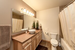 A bathroom with a sink, mirror, toilet, and shower curtain. - Tiger Lilly Lodge (Cle Elum)