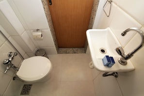 A small bathroom with a toilet, sink, and shower.