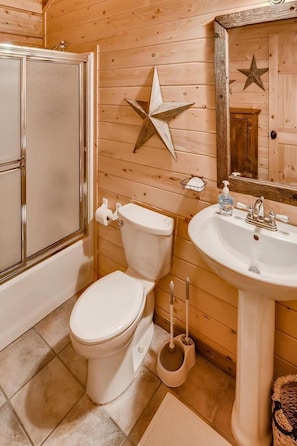 Un baño con pared de madera, inodoro blanco, lavamanos y decoración con estrellas.
