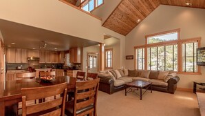 A spacious living area with a large wooden dining table, comfortable seating, and a view of the outdoors through large windows. - Roslyn Hideaway (Cle Elum)