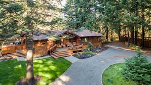 A log cabin with a deck, outdoor seating, and a gravel driveway. - Yakima River Retreat (Cle Elum)