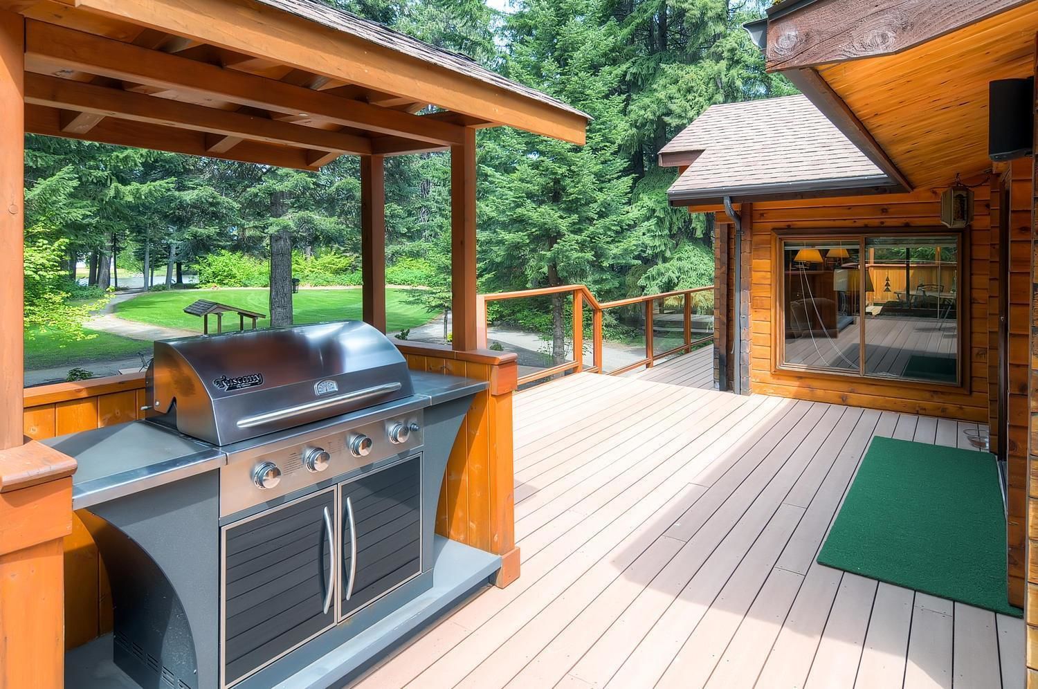 A wooden deck with a built-in grill and a glass door leading to an indoor area.