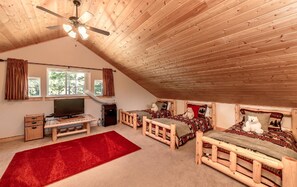 A cozy attic bedroom with wooden beams, a ceiling fan, a TV, and two beds with dog-themed bedding. - Wintergreen Retreat (Cle Elum)