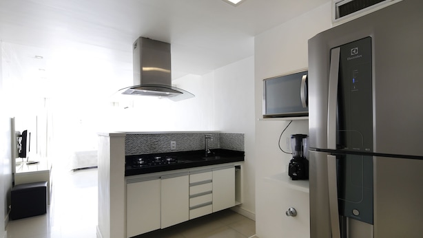 Eine moderne Küche mit einem Edelstahl-Kühlschrank, einer integrierten Mikrowelle und einer schwarzen Arbeitsplatte.