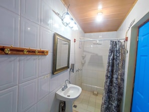 A bathroom with a sink, mirror, shower, and a wooden ceiling. - Hotel Fuente de Paz Managua es Posada de Paz  (Managua)