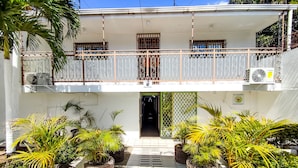 Un bâtiment à deux étages doté d’un balcon, de plantes en pot et d’un appareil de climatisation.