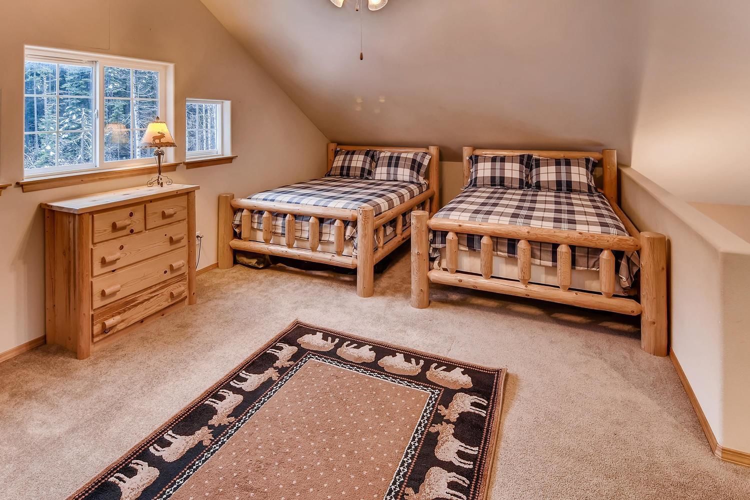 A bedroom with two wooden beds, a wooden dresser, and a rug with animal patterns.