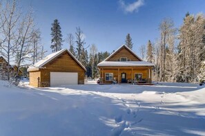 A wooden cabin with a garage, surrounded by snow-covered trees. - Roslyn Chalet (Cle Elum)