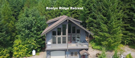 A two-story building with a balcony, surrounded by dense forest.