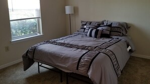 A bedroom with a bed, a window, and a floor lamp. - Condo near IMG Academy & Beaches (Bradenton)
