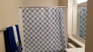A bathroom with a shower curtain featuring a geometric pattern, a toilet, and a sink with a mirror above it. - Condo near IMG Academy & Beaches (Bradenton)