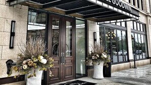 The exterior of Hotel Goodwin with a classic stone facade, large glass windows, and a prominent entrance with a black awning.