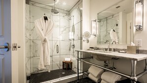 A modern bathroom with a glass-enclosed shower, a vanity with a mirror, and a towel rack.