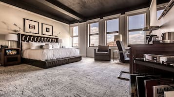 Ein Schlafzimmer mit einem großen Bett, einem Sessel, einem Schreibtisch und einem Bücherregal.