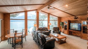 Un salon confortable avec une grande fenêtre donnant sur un lac, une cheminée et un téléviseur.